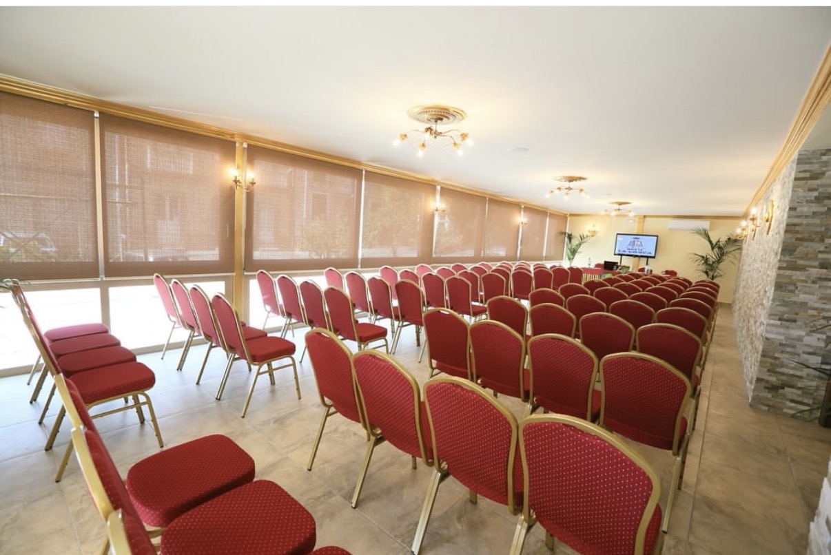 Sala meeting allestita a platea con sedie rosse e schermo