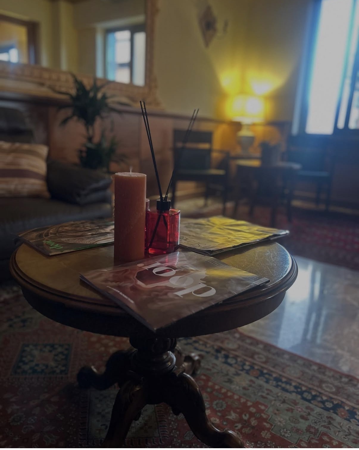 Salotto della hall con tavolino in legno, candela e riviste